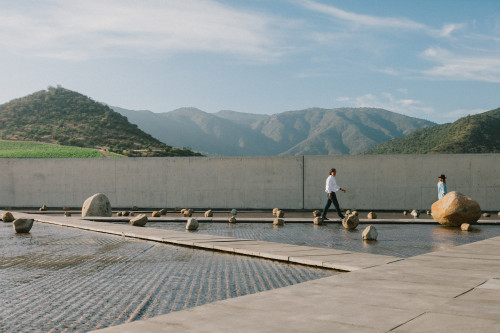 Exterior Constanza Miranda  water rocks footpath path  mountains landscape couple walking woman man hat sky clouds crops Sloping Plaza architecture winemaker Cristián Vallejo