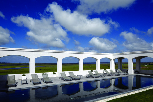 Estancia VIK Jose Ignacio Uruguay swimming pool blue sky clouds lounging chairs landscape nature green water