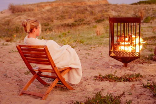 Beachfront fire La Susana Restaurant José Ignacio Uruguay brazier woman sand blanket chair bush exterior