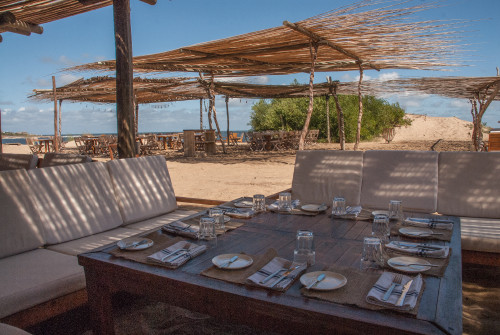 La Susana Restaurant José Ignacio Uruguay exterior sand sofa beach sea water blue sky bush chair setting table glass oil vinegar napkin fork knife butter plate cutlery dining room