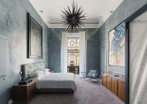 Galleria VIK Milano Italy Palace Rooms Suites 208 Mario Schifano night table bedroom 
double bed
door 
headboard lamps books pillows window view Prada Vittorio Emanuele II balcony