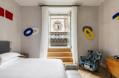 Galleria VIK Milano Italy Suites Deluxe Gallery Rooms  323 Pinelli bedroom double bed headboard pillows night table lamps armchair window view curtains sculpture books furniture steps stairs balcony bench