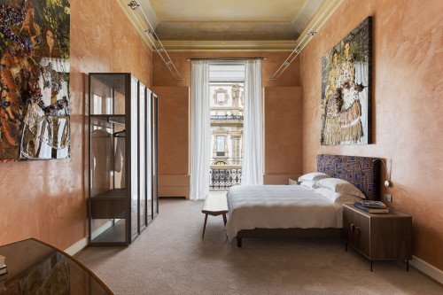 Galleria VIK Milano Italy Suites  Palace Room 207 Nina Surel bedroom double bed headboard pillows night table lamps books paintings furniture window view curtains balcony closet bench Vittorio Emanuele II