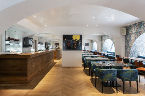 Galleria VIK Milano Italy Vikissimo Restaurant chairs tables window glass red wine setting TV paintings napkins fork knife oranges