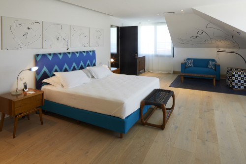 Bahía VIK José Ignacio Main Building Suites Eva bedroom double bed headboard pillows night table lamps telephone sofa armchair bench carpet paintings wall door cushions curtains window telephone lights