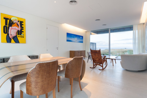 Bahía VIK José Ignacio Vidrio Notas Bungalow living  dining room sofas chairs table window view sea wood curtains furniture paintings poster 
rocking sand bush lights interior armchair