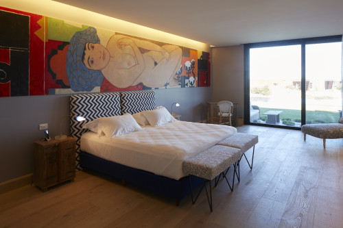 Bahía VIK José Ignacio Pemper Suite Main Building bedroom double bed headboard pillows night table lamps chair desk painting bench window view grass interior telephone