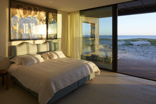 Bahía VIK José Ignacio Suave Suite Zinc Marrón bungalow bedroom double bed headboard pillows night table lamps sand shadow window view curtains interior