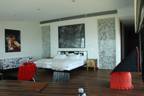 Playa VIK José Ignacio Uruguay Guest Suites interior Valentina Suite  armchair window carpet red furniture bedroom double bed headboard pillows night table lamps blanket photograph chair desk telephone black white