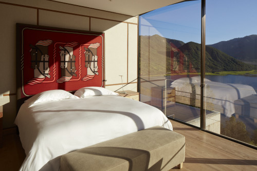 H Master Guest Suite Hotel VIK Chile interior bedroom window view mountains valley lake reservoir painting lamps night table double bed headboard pillows bench