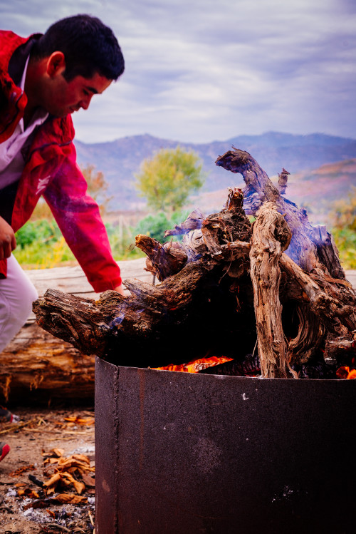 red green fire flame brazier trees trunk mountains  man jacket sky clouds