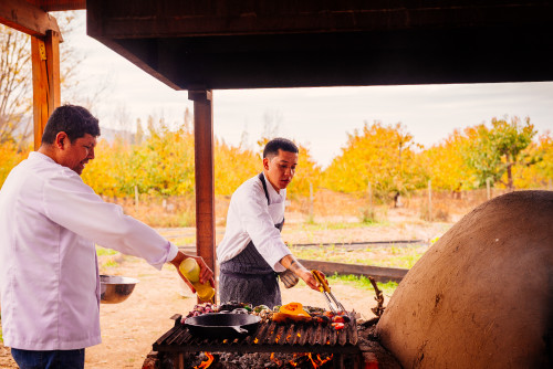 clay oven skillet vegetables  eggplant  barbecue tongs yellow trees firewood fire embers men orchard tomato pepper purple onion pumpkin chef oil