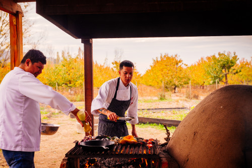 clay oven skillet vegetables  eggplant  barbecue tongs yellow trees firewood fire embers men orchard tomato pepper purple onion pumpkin chef