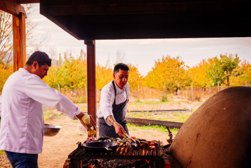 clay oven skillet vegetables  eggplant  barbecue tongs yellow trees firewood fire embers men orchard tomato pepper purple onion pumpkin chef