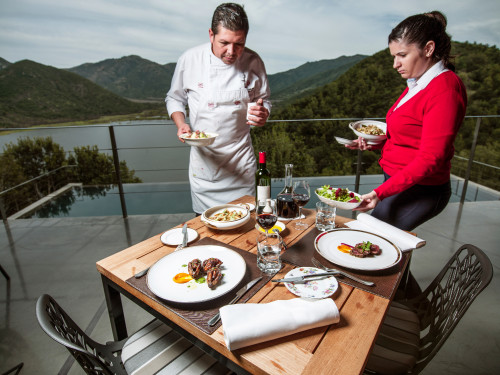 VIK Hotel swimming pool chef table food plates chairs glass fork knife red wine napkin consumption salad meat man woman mountains landscape nature trees lake reservoir decanter view