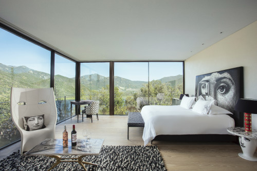 Interior VIK Hotel Room Master  Fornasetti Suite double window view landscape reservoir carpet bedroom double bed chair table desk mountains nature  cushion trees green Guest Chile lake bottle glass La Piu Belle rosé red wine bench backrest lamp Juan Pablo Jaramillo