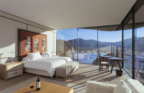 Master Guest Suite Hotel VIK Chile interior bedroom window view mountains valley lamps night table double bed headboard pillows Hermes Juan Pablo Jaramillo bottle red wine glass sofa bench chair