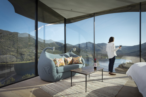 VIK Hotel Juan Pablo Jaramillo Bottle landscape window view sofa lamps glass red wine valley mountains bed double cushions carpet lake reservoir woman glass Chile